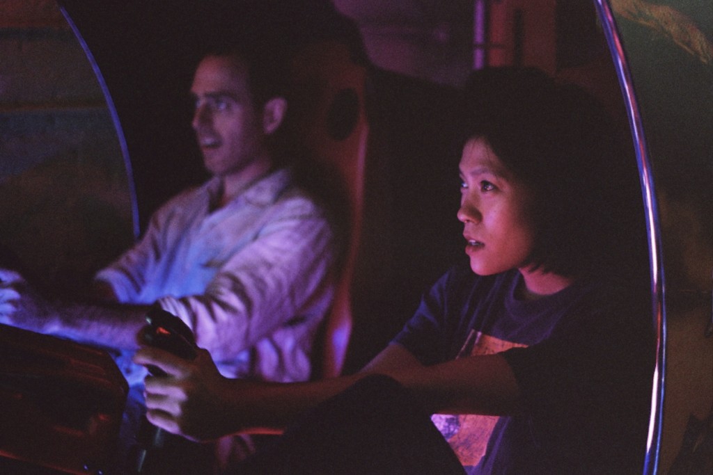 still from The Lost Arcade, showing a man and a woman sitting next to each other in an arcade cockpit, faces focused on action off screen